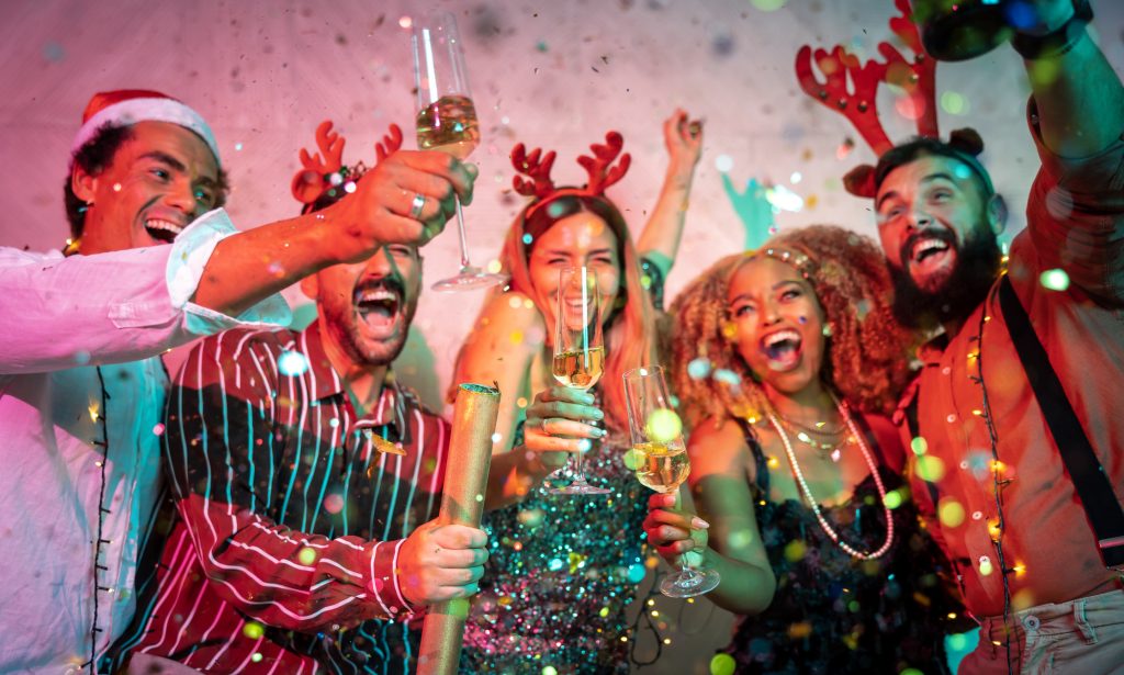 People having fun at Christmas party, dancing, singing, throwing confetti and making a toast